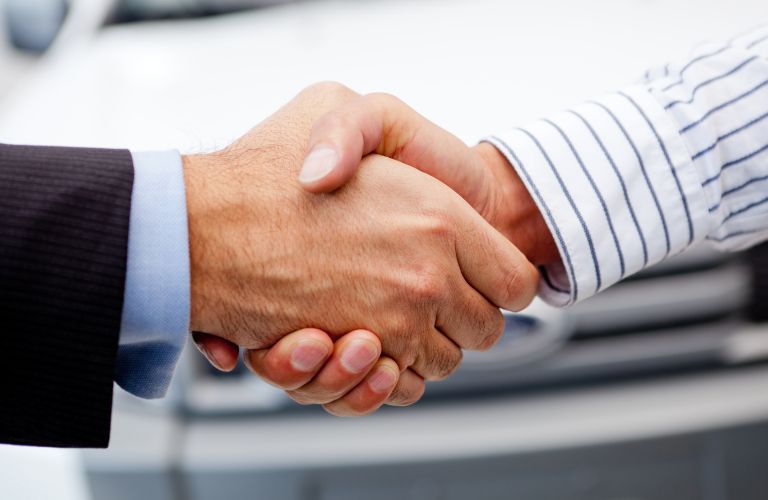 Close Up of Car Dealer and Car Shopper Shaking Hands