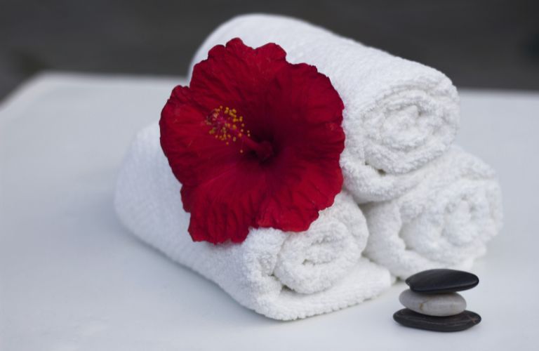Red Flower on Stack of White Folded Towels