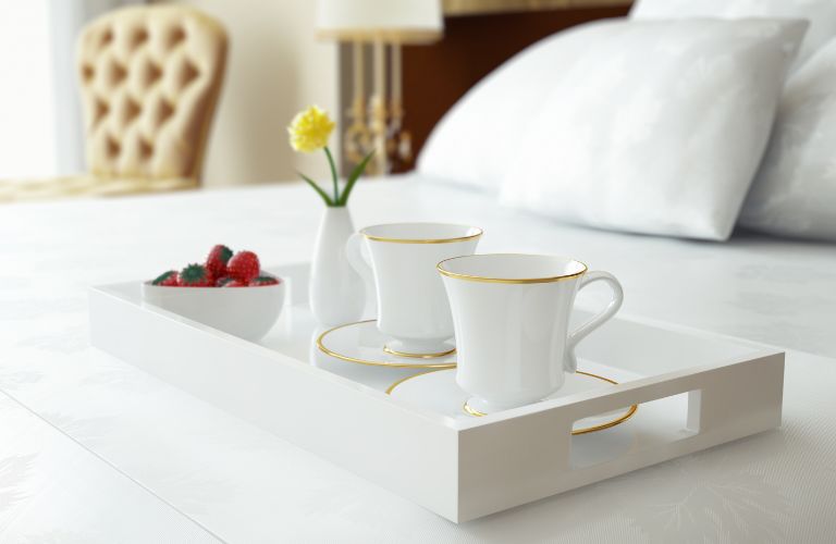 Room Service Tray with Dishes and Flowers on a Bed