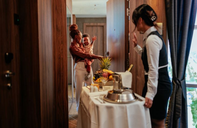 Woman Bringing Room Service to Woman and Child in a Hotel Room