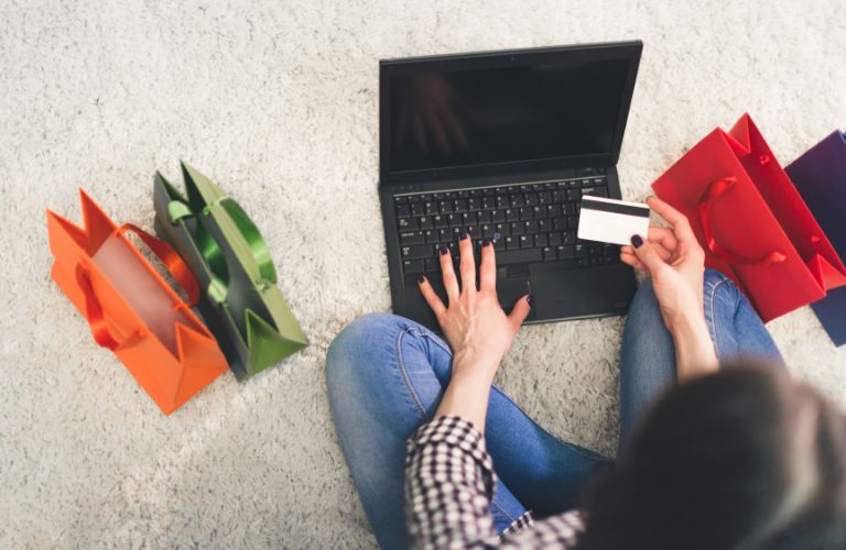 Woman Sitting on the Floor with Laptop, Credit Card and Bags