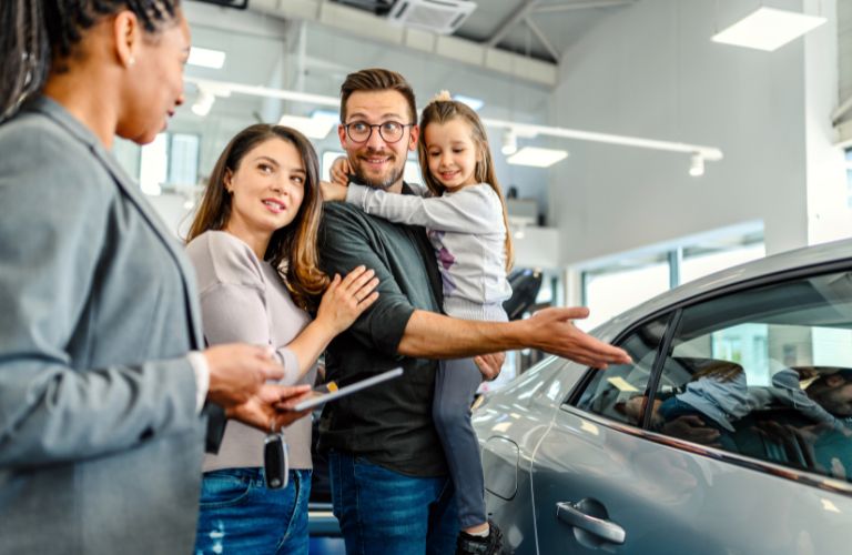 Family Looking at a Car with a Car Dealer