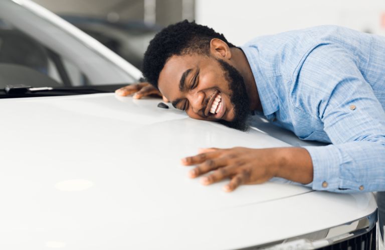 Happy Man Laying on the Hood of a White Car
