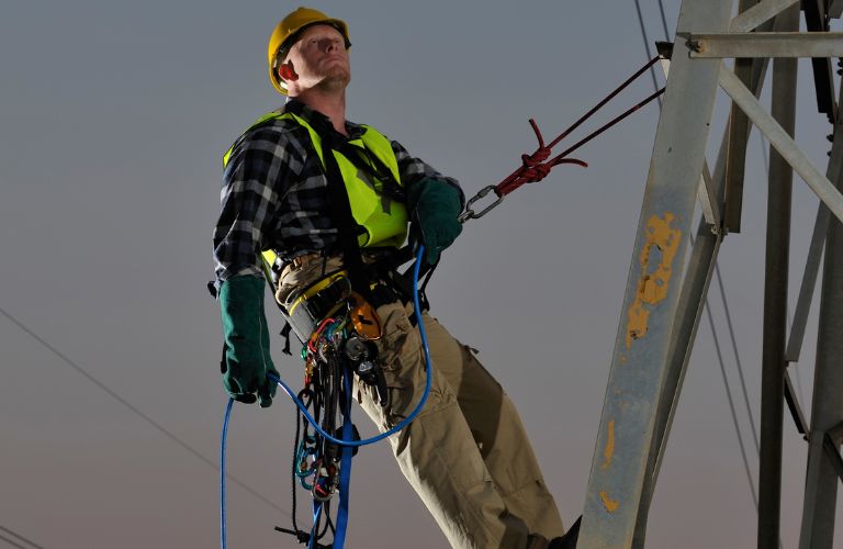 Electrical Worker Climbing a Steel Electrical Pole
