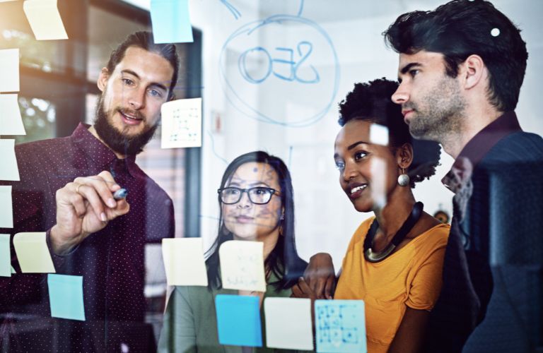 Employees Working on SEO Strategy on a Clear Board with Sticky Notes