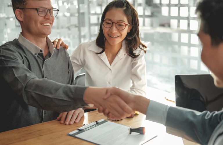 Happy Couple Shaking Hands with Insurance Agent