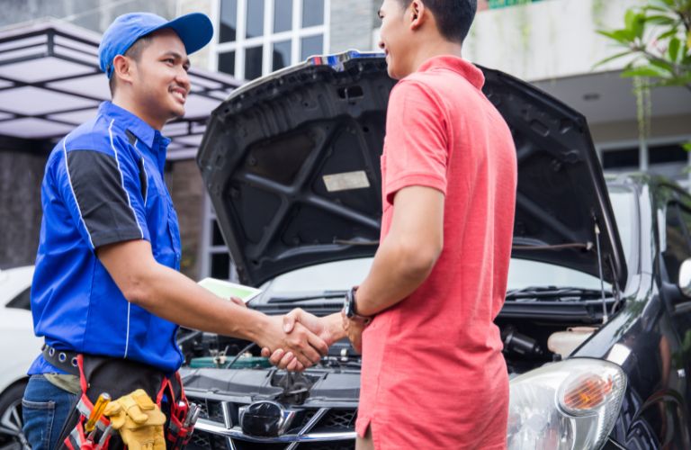 Man Shaking Hands with Mechanic in Front of a Car